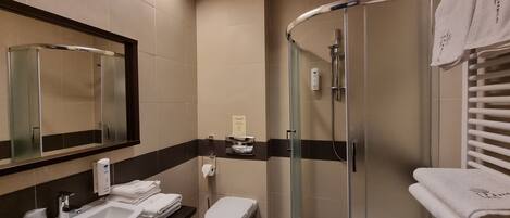 Un baño moderno con lavabo, inodoro y ducha con mampara de vidrio.