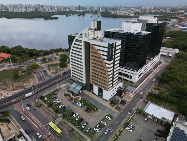 Un moderno complejo de edificios con fachada curva, estacionamiento contiguo y vista a un río tranquilo.