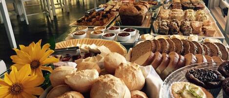 A buffet with various breads, pastries, and desserts.