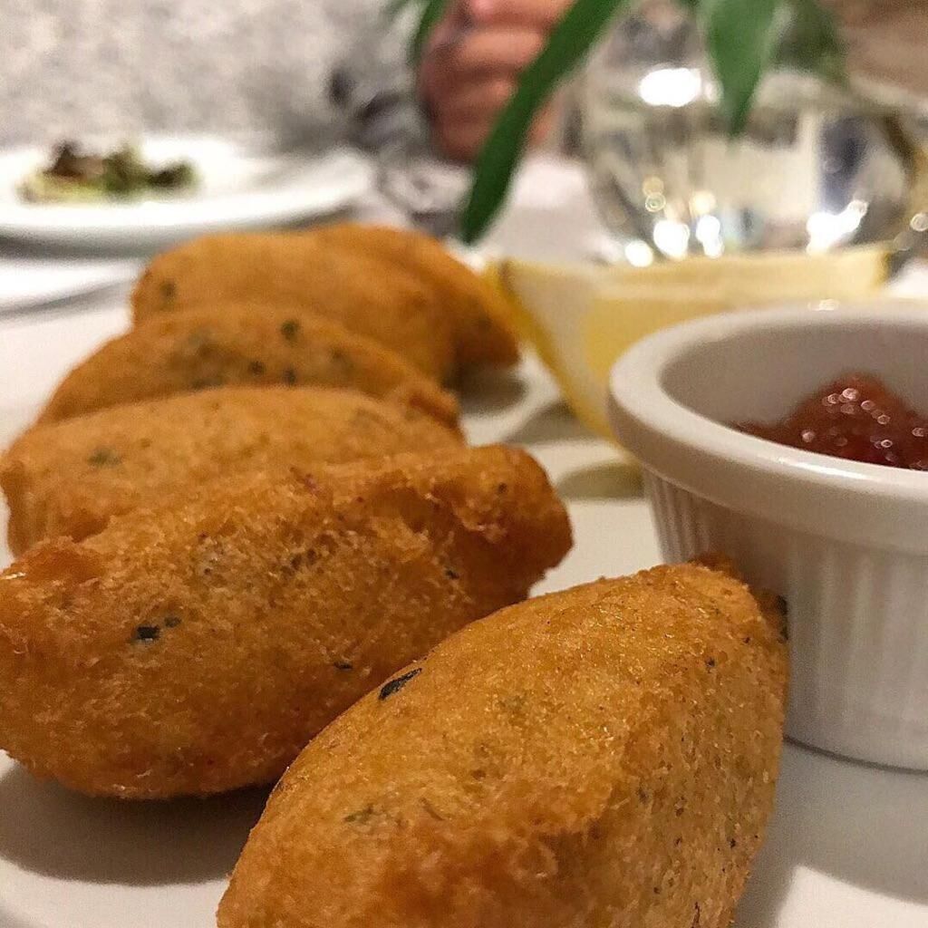 Um prato com croquetes e uma pequena tigela de molho.
