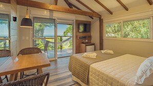 Un dormitorio con cama, televisor, escritorio y comedor.