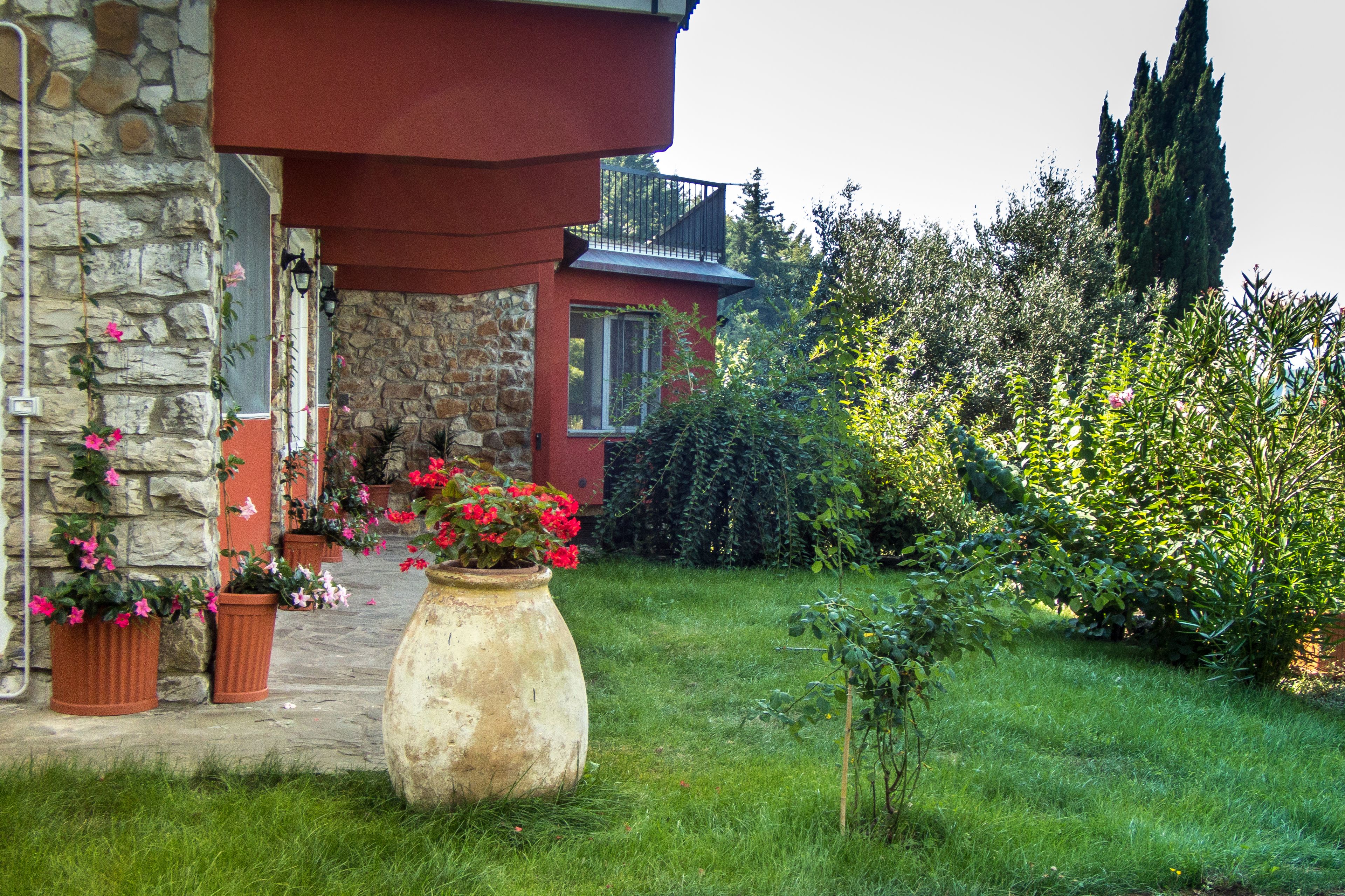 A stone building with a red upper section, a balcony, and potted plants in the foreground.
