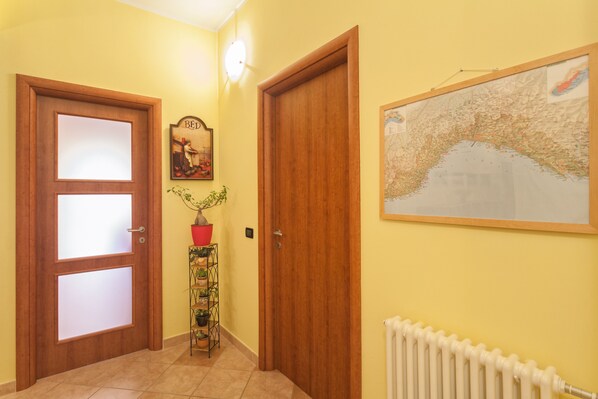 Un pasillo con dos puertas de madera, un mapa en la pared y un radiador.