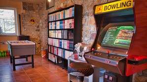 A room with a foosball table, a bowling machine, and a bookshelf filled with books. - Oasi Verde (Castiglione Chiavarese)