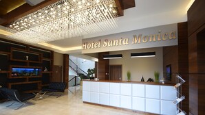 A modern hotel lobby with a reception desk, seating area, and a staircase leading to other floors. - Hotel Santa Monica (Mikolajki)