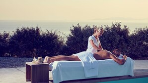 En person får en massage vid poolkanten med utsikt över havet.