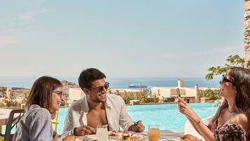 Enjoy a casual meal with a view of the pool and the sea.