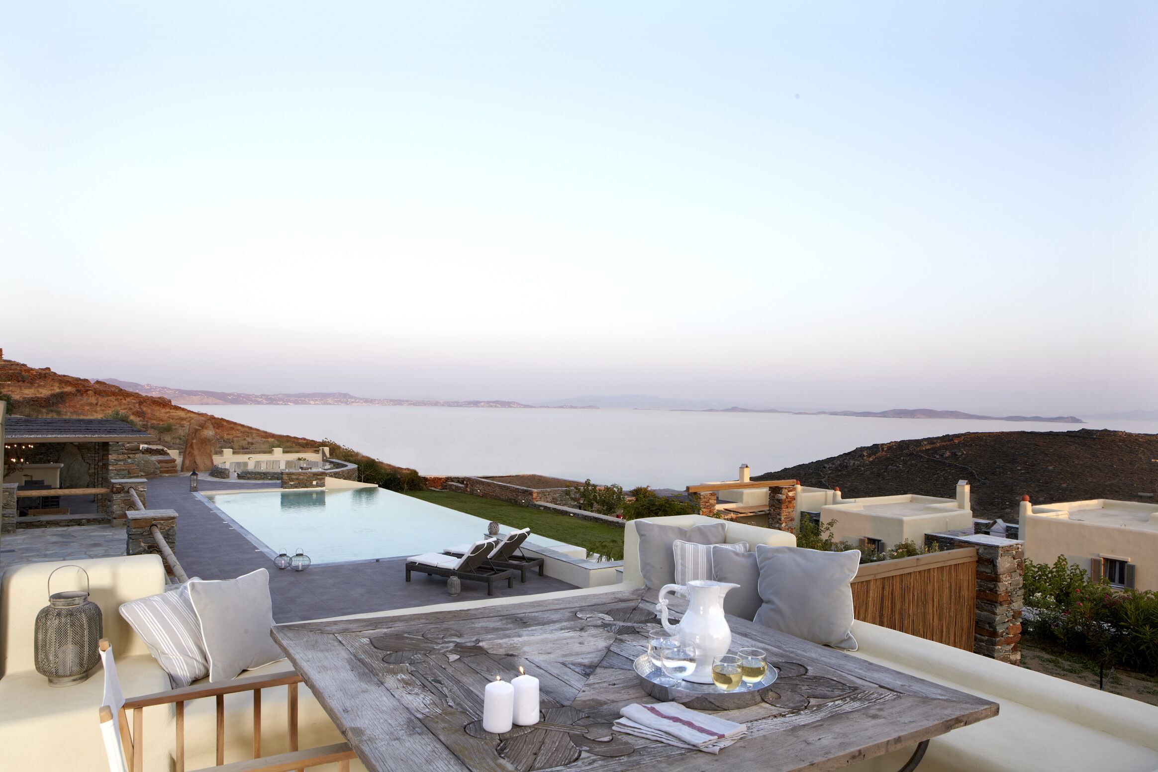 Terraço no telhado com piscina, espreguiçadeiras e mesa posta para refeições.