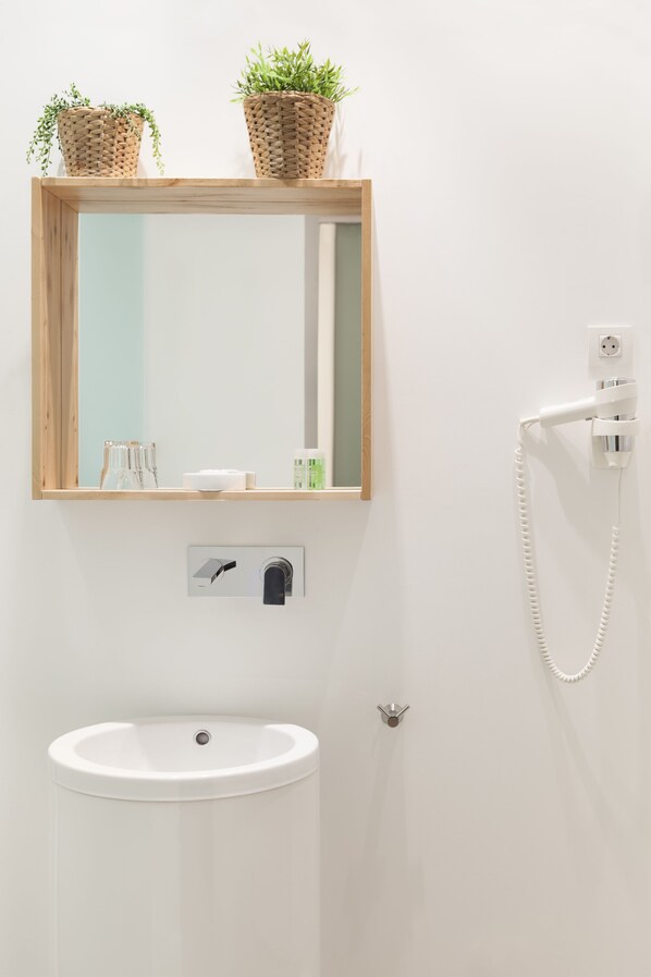 Un baño con un espejo de marco de madera, un lavabo blanco y un teléfono instalado en la pared.