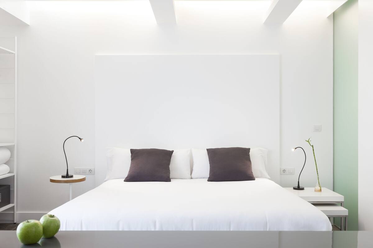 A modern hotel room with a large bed, two bedside tables, and a nightstand.