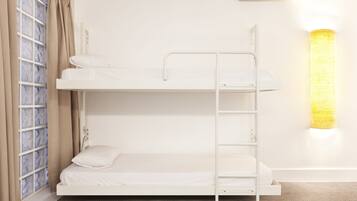 A bunk bed with a ladder, a window with curtains, and a wall-mounted light fixture.