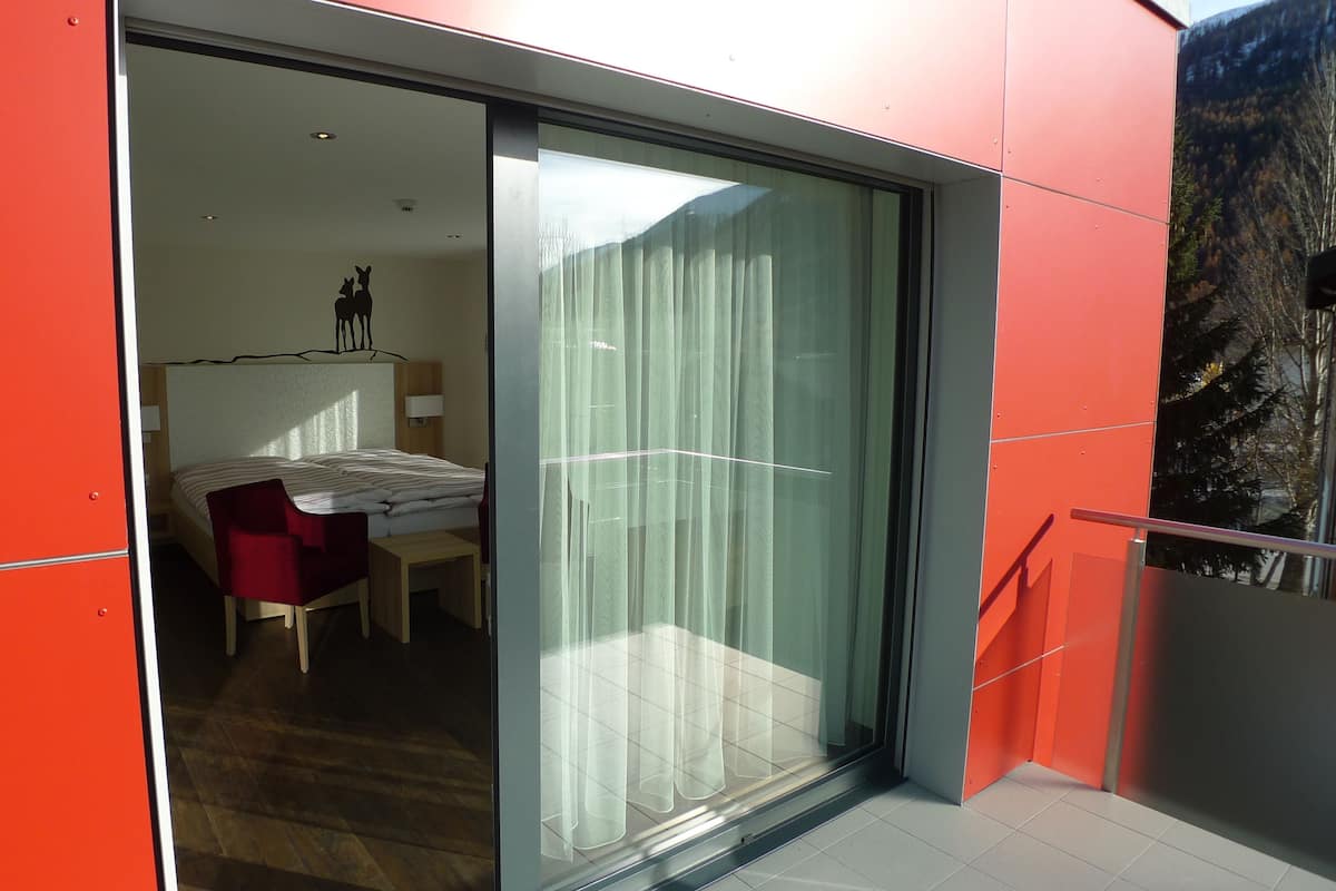 A modern hotel room with a bed, a desk, and a chair.