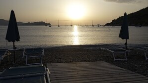 A beach with a wooden deck, lounge chairs, and umbrellas. - Residenza Sant'Anna del Volterraio (Rio)