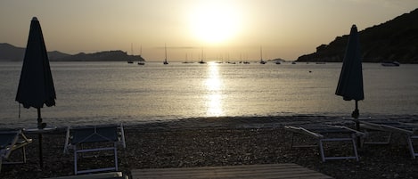 Ein Strand mit einer Holzterrasse, Liegestühlen und Sonnenschirmen.