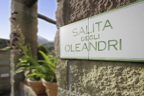 A sign with the text "SALITA DEGLI OLEANDRI" mounted on a stone wall. - Residenza Sant'Anna del Volterraio (Rio)