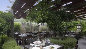 An outdoor dining area with wooden tables and chairs, surrounded by greenery and a pergola structure. - Residenza Sant'Anna del Volterraio (Rio)