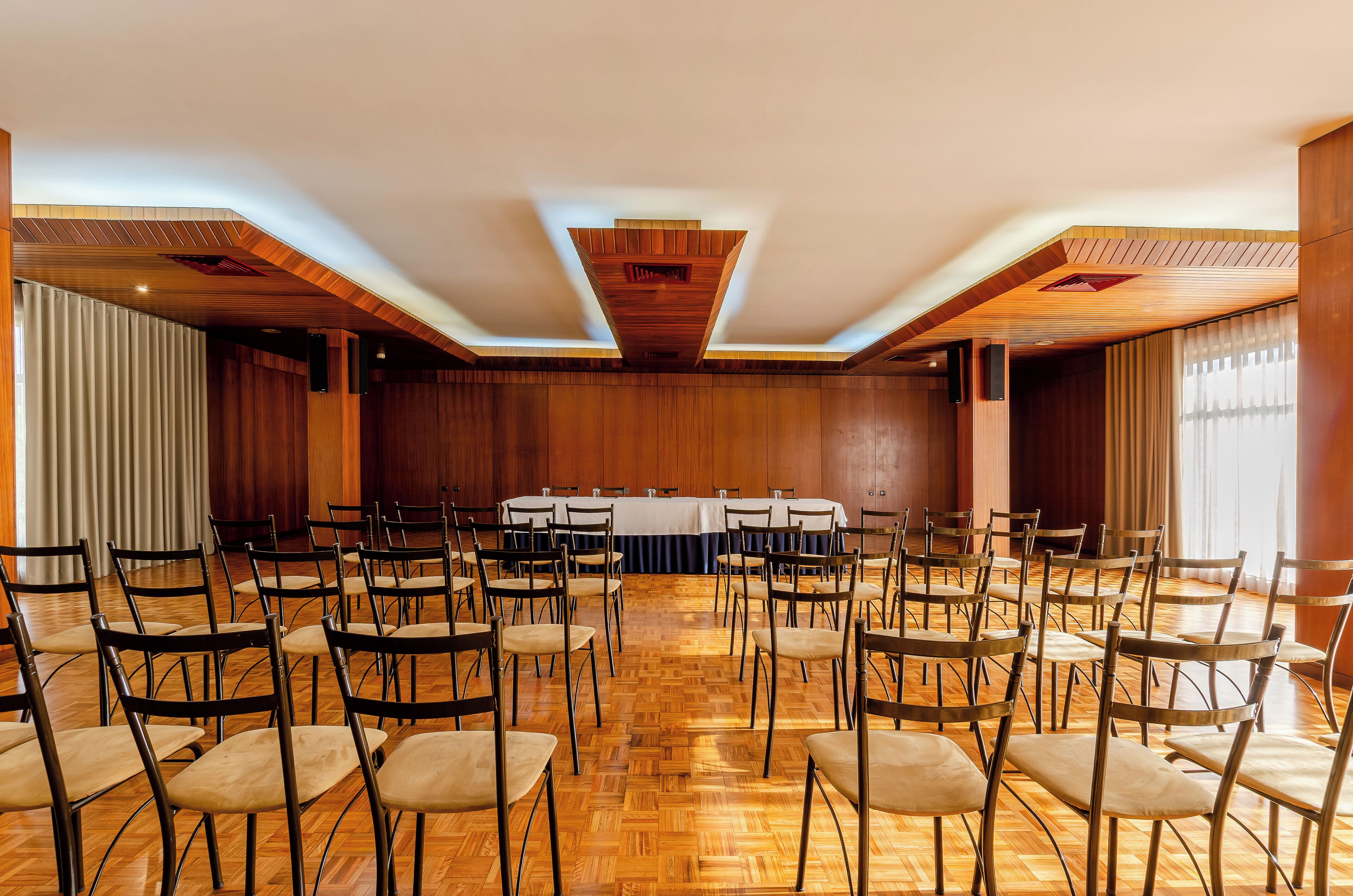 A conference room with a long table, multiple chairs, and wooden paneling on the walls.
