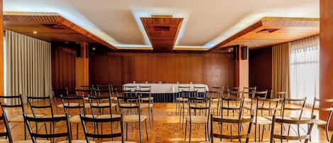 A conference room with a long table, multiple chairs, and wooden paneling on the walls.