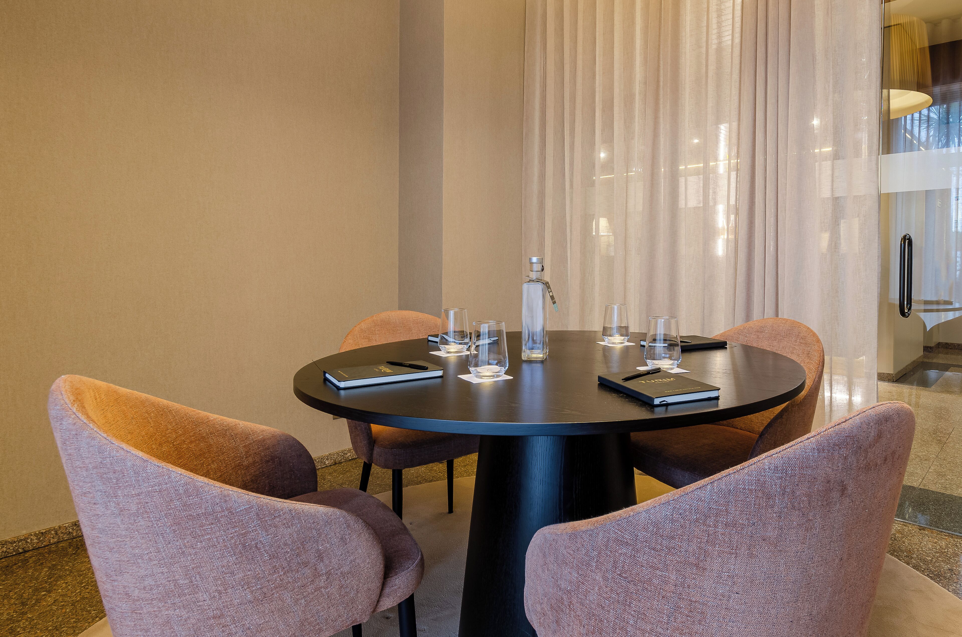 A round table with six chairs, a bottle, and glasses on it.
