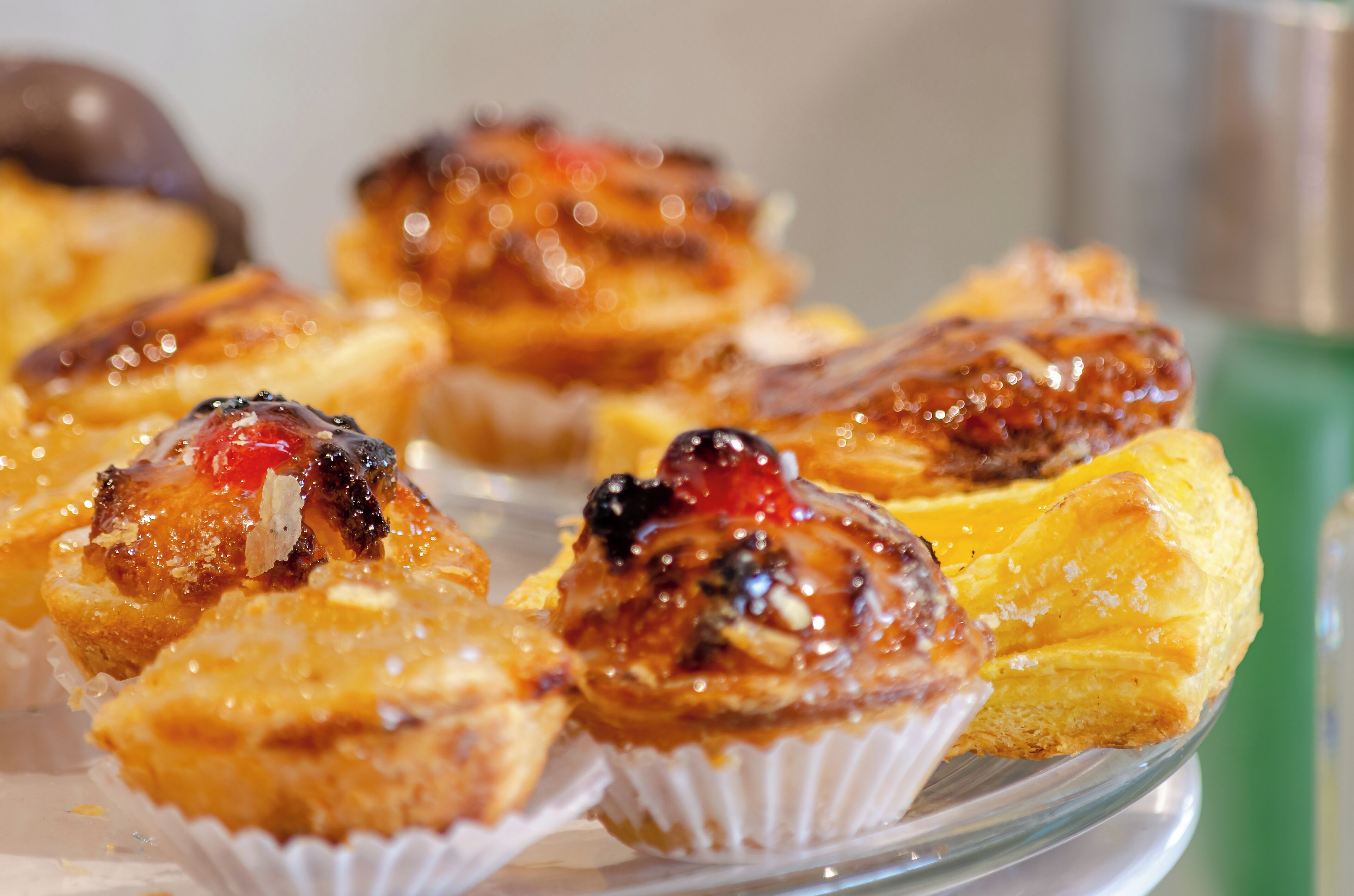 A plate of pastries with a glossy glaze and fruit toppings.