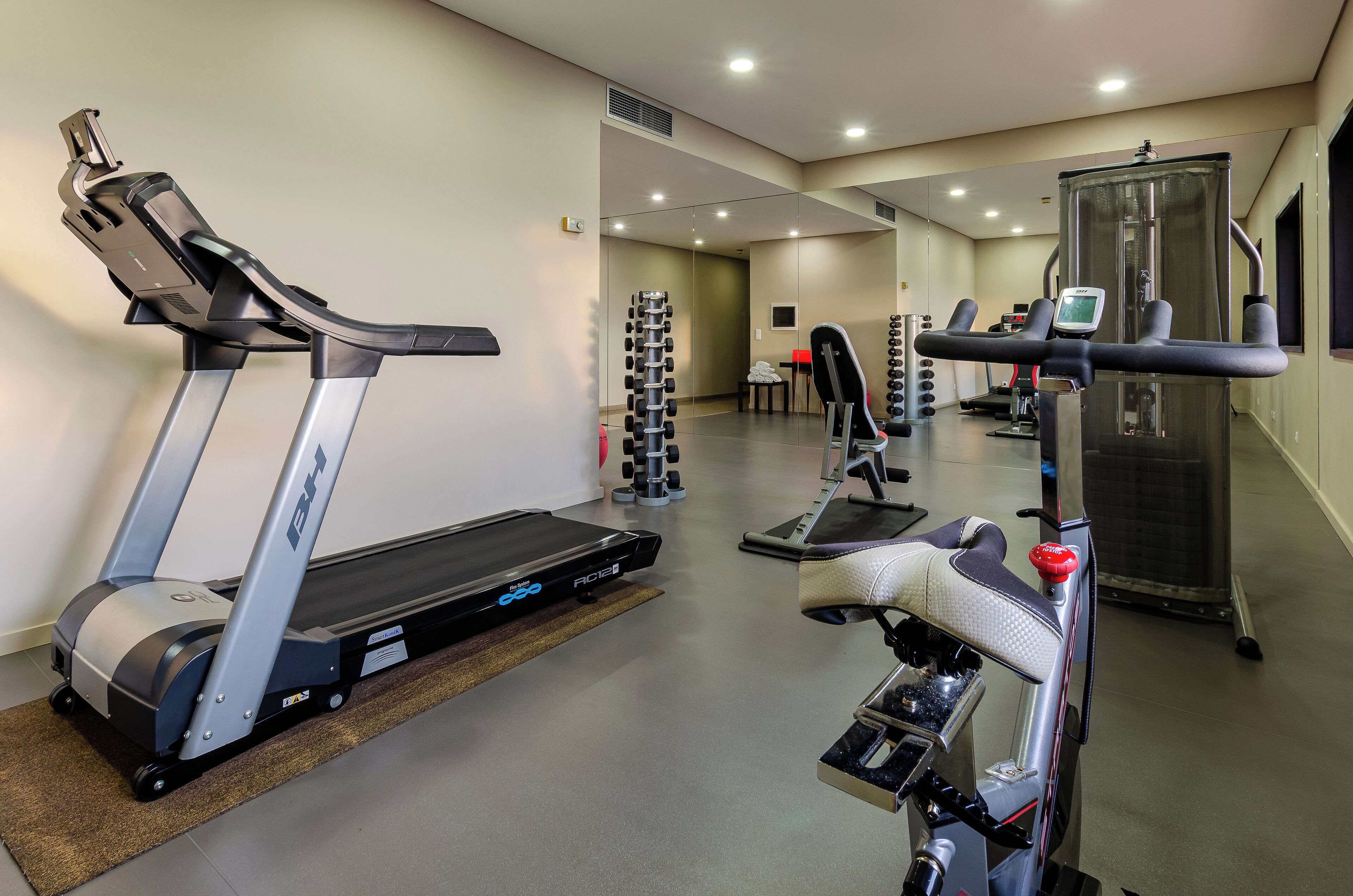 Un gimnasio con cintas de correr, una bicicleta estática y una torre de pesas.