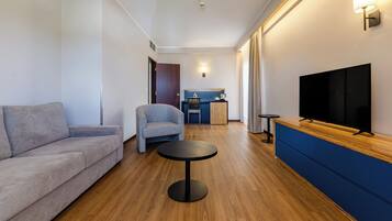Ein modernes Wohnzimmer mit einer Couch, einem Sessel, einem runden Couchtisch und einem Fernseher auf einem Holzschrank.
