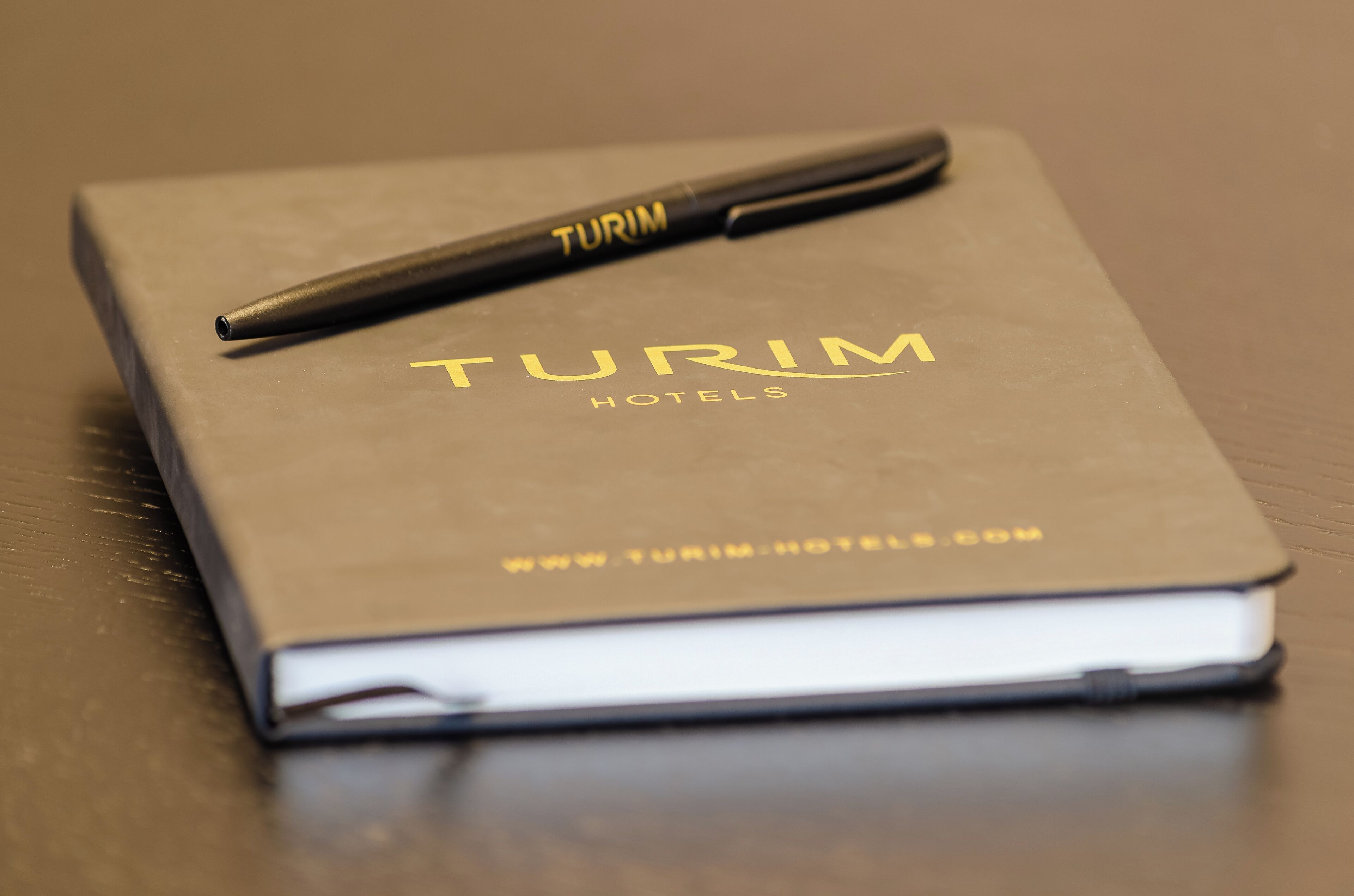 Un cuaderno de hotel TURIM con un bolígrafo encima.