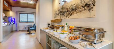 A modern kitchen with a buffet setup, including various food items and a toaster.