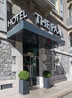 Exterior del Hotel PAX, con fachada de piedra, una entrada moderna con puertas de vidrio y dos macetas en la entrada.