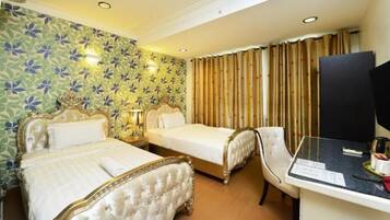 A hotel room with two beds, a desk with a computer, and a television.