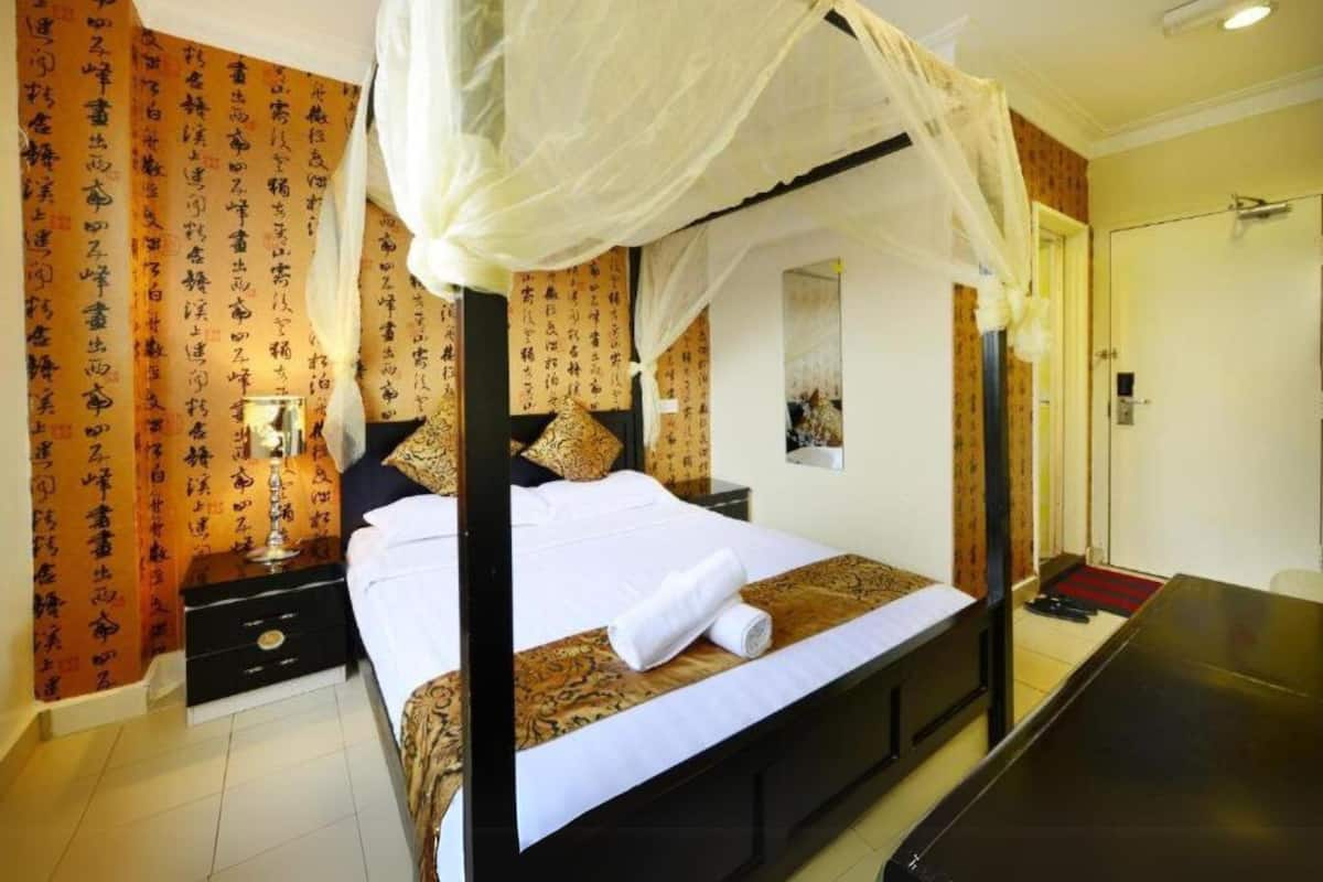 Quarto de hotel com cama de dossel, mesa de cabeceira e espelho.