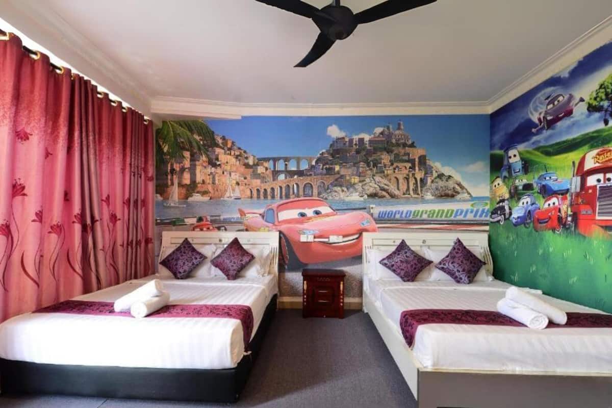 Quarto de hotel com duas camas, um mural de uma cidade costeira e uma parede com tema do filme Carros.