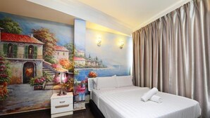 A hotel room with a large bed, a nightstand with a lamp, a painting of a coastal scene, and a view of the sea through the window. - Seeds Hotel Shah Alam Seksyen 7 I-City (Shah Alam)