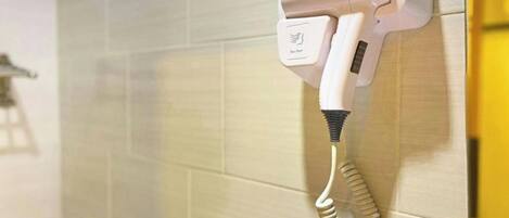 A hair dryer mounted on a tiled wall in a bathroom.