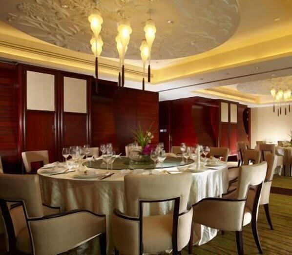 A formal dining room with round tables set for a meal, featuring chandeliers and wooden paneling. - New Century Grand Hotel Tonglu Hangzhou China (Hangzhou)