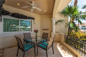 A balcony with a table and chairs, a ceiling fan, and a view of palm trees. - Aventuras Club Lagoon (Puerto Aventuras)