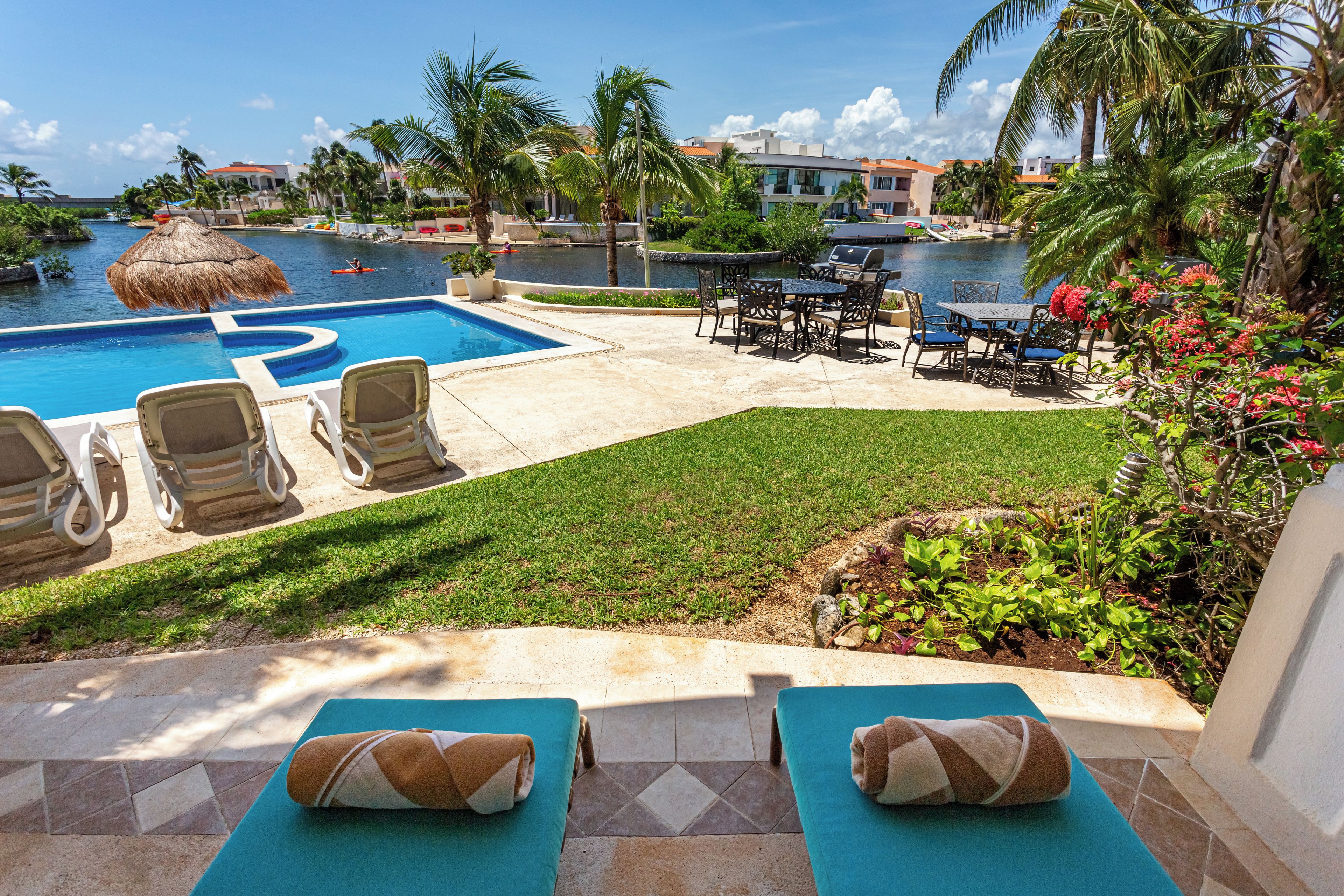 Zona de piscina con sillas de descanso, una parrilla y vistas al agua.