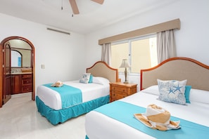 A hotel room with two beds, a window with curtains, a wooden nightstand, and a mirror. - Aventuras Club Lagoon (Puerto Aventuras)