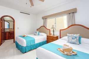 Habitación de hotel con dos camas, una ventana con cortinas, una mesita de noche de madera y un espejo.