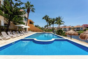 Una piscina con sillas de descanso y palmeras.