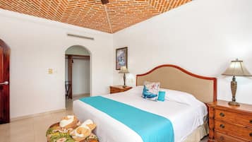Un dormitorio con techo de ladrillo, una cama con colcha azul, mesitas de noche de madera y una silla de mimbre.