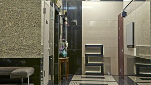 A modern hallway with a geometric patterned floor, a seating area, and a staircase. - Brown Suites Seoul (Seoul)