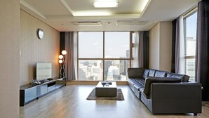 A modern living room with a large window, a sofa, a coffee table, and a TV on a stand. - Brown Suites Seoul (Seoul)