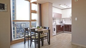 A modern kitchen with a view of the city, a dining area with a table and chairs, and a washing machine. - Brown Suites Seoul (Seoul)