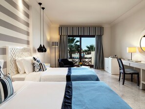 Habitación de hotel con dos camas, un escritorio, una silla, una lámpara y vistas al exterior.