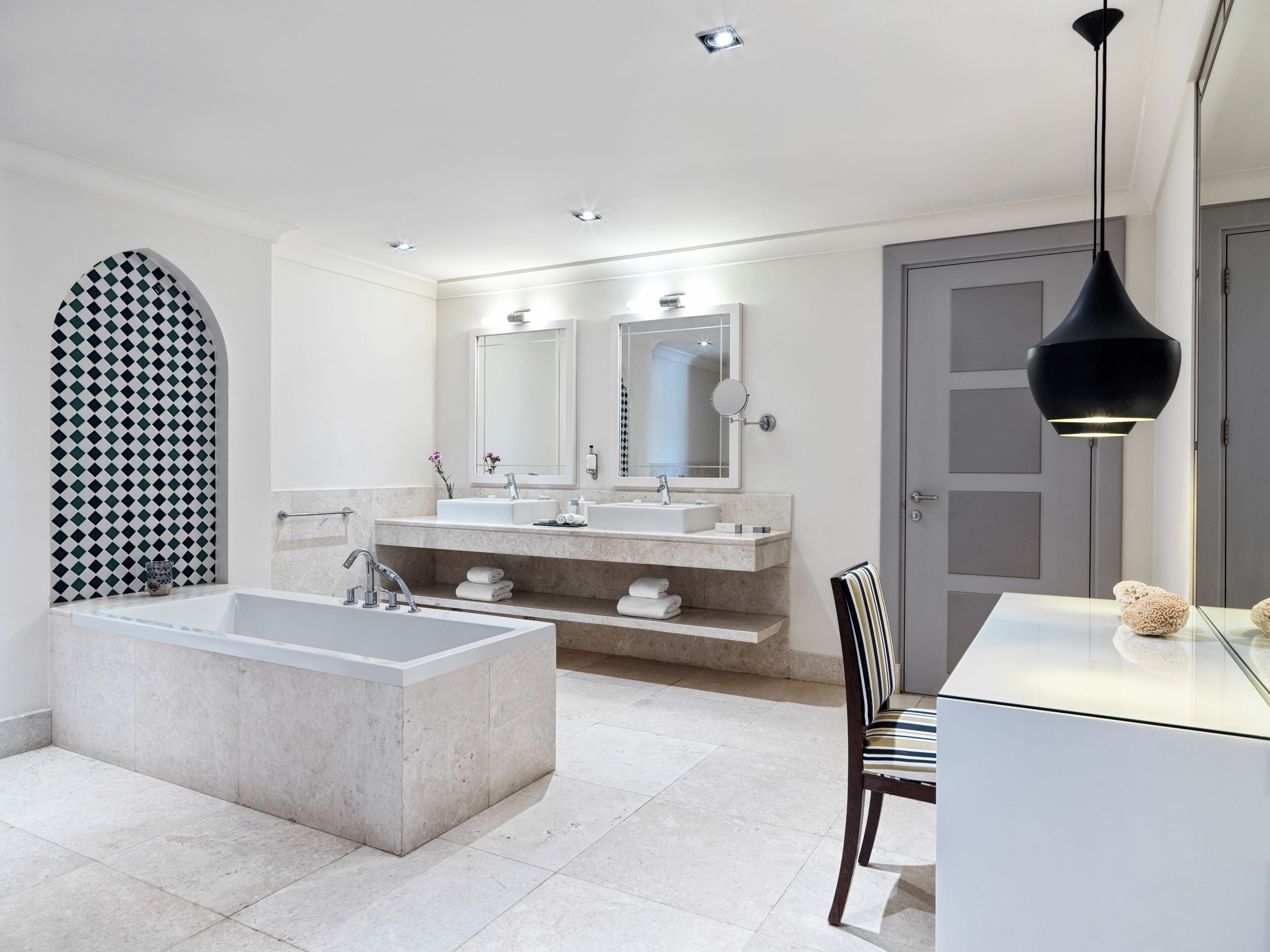 Un baño moderno con una bañera independiente, un tocador doble y un espejo grande.