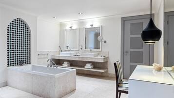 Un baño moderno con una bañera independiente, un tocador doble y un espejo grande.