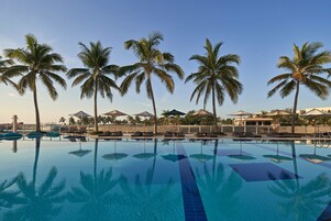 Una piscina cristalina rodeada de palmeras y sillas de descanso.