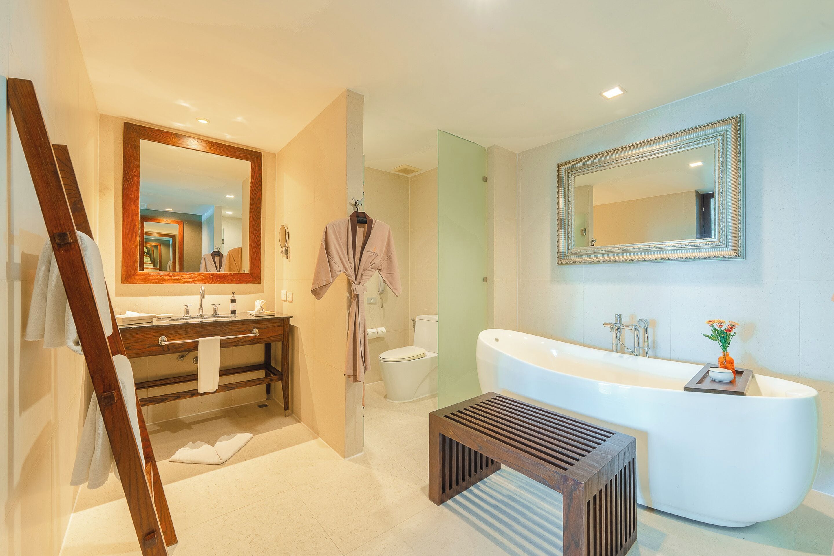Une salle de bain moderne avec une baignoire sur pieds, un grand miroir et un banc en bois.