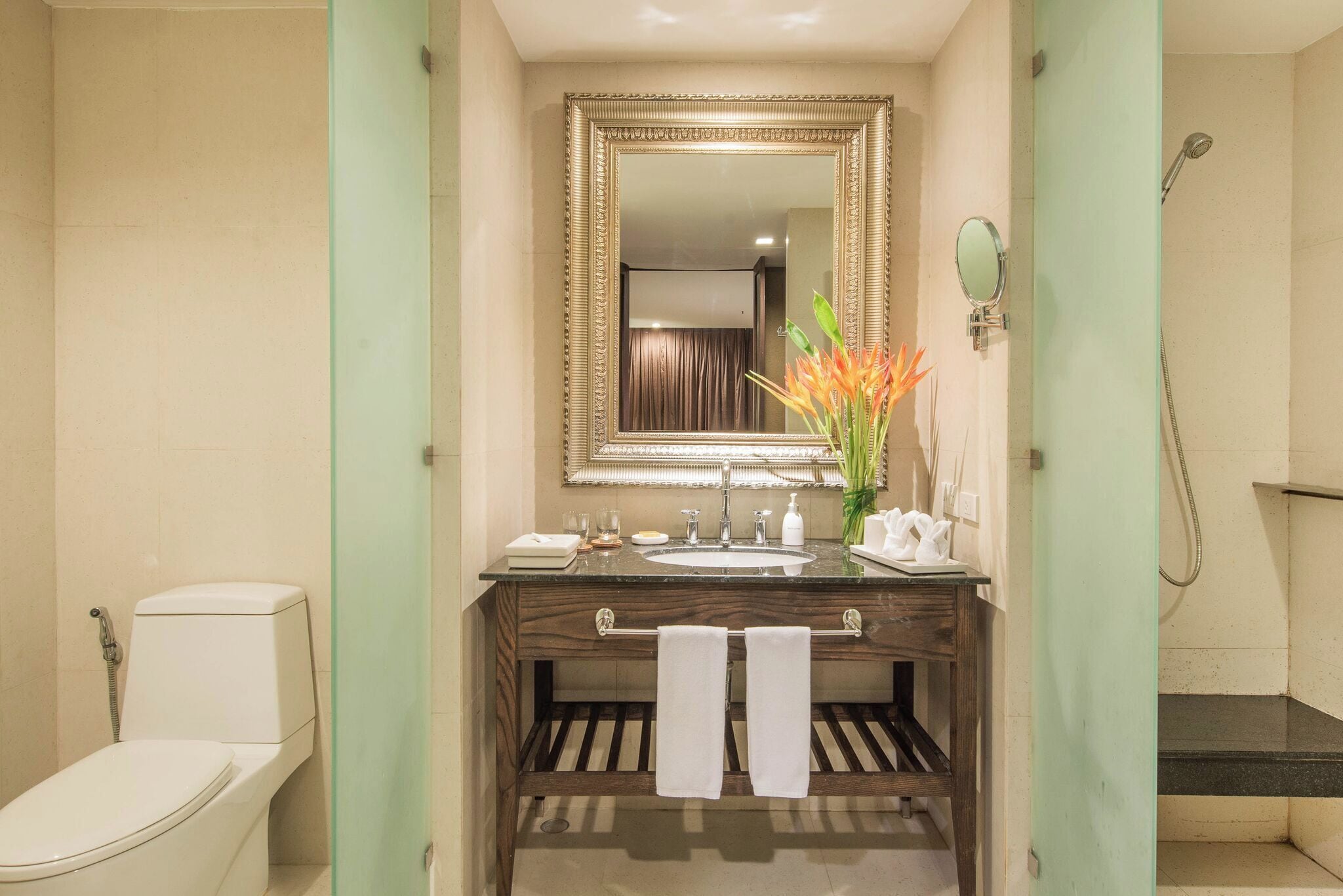 A bathroom with a toilet, sink, mirror, and shower.